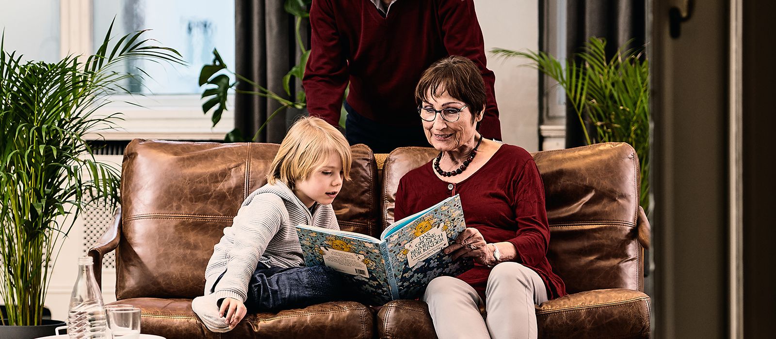 Großeltern lesen ihrem Enkel aus einem Buch vor.