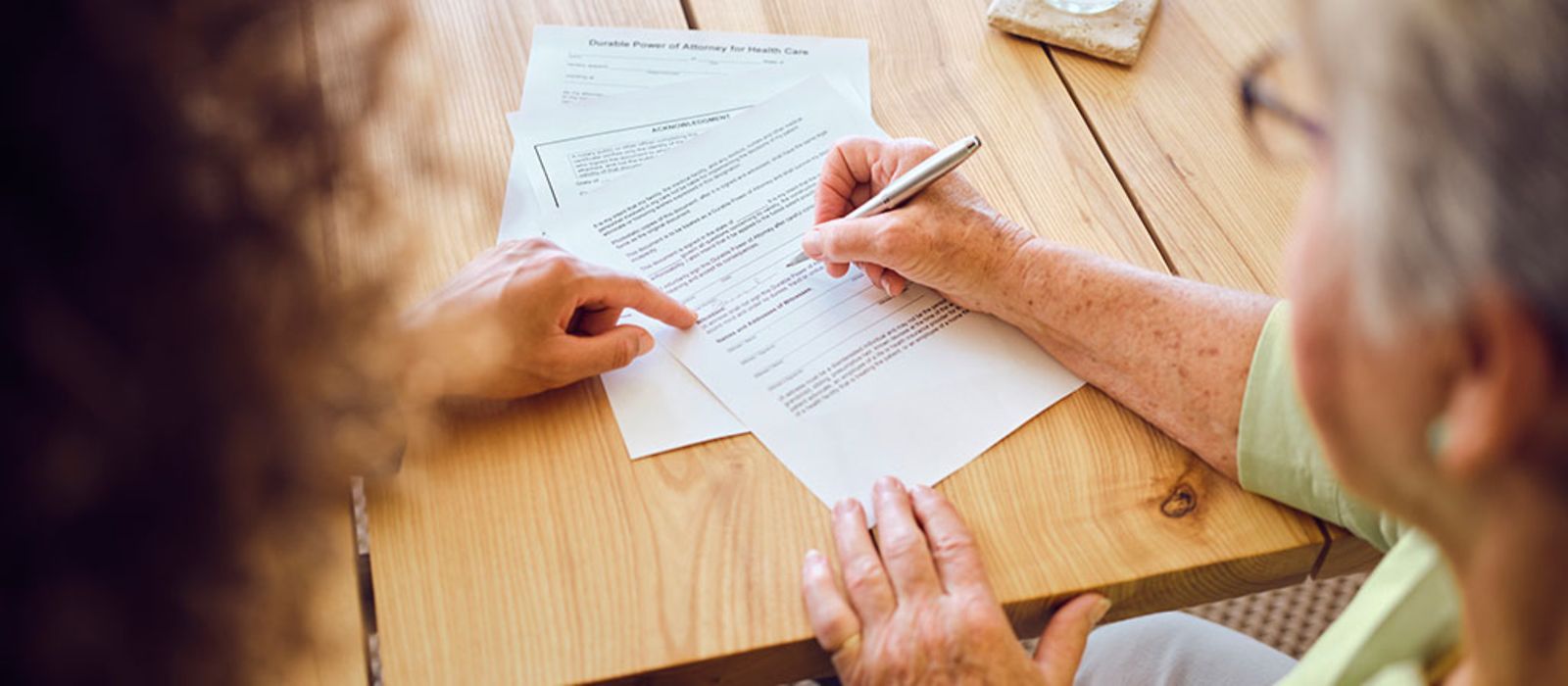 Eine ältere Dame unterschreibt einen Vertrag.