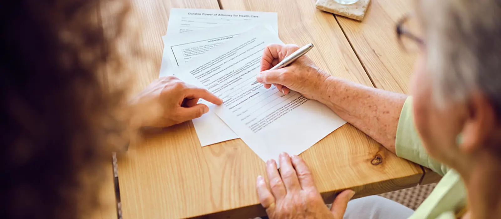 Eine ältere Dame unterschreibt einen Vertrag.