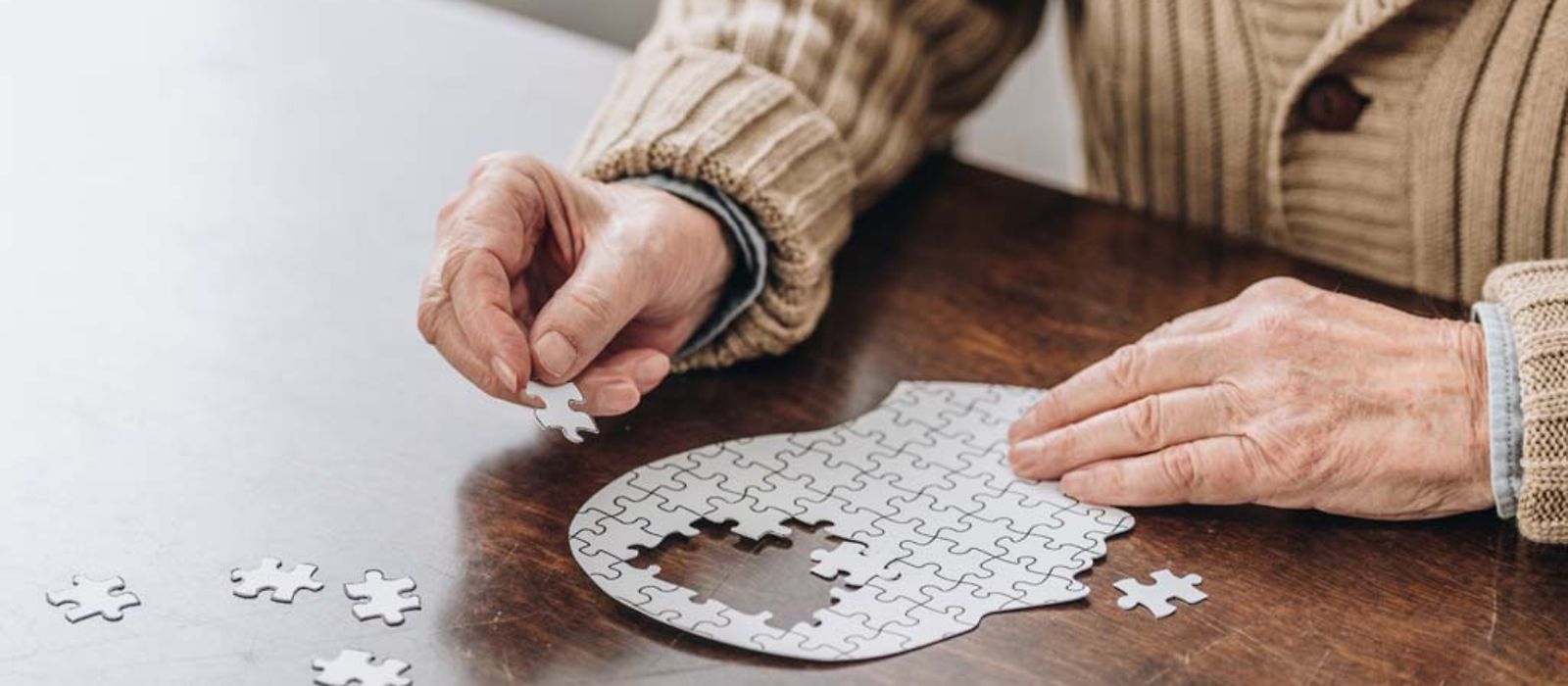 Senior puzzelt den Umriss eines Kopfes zusammen.
