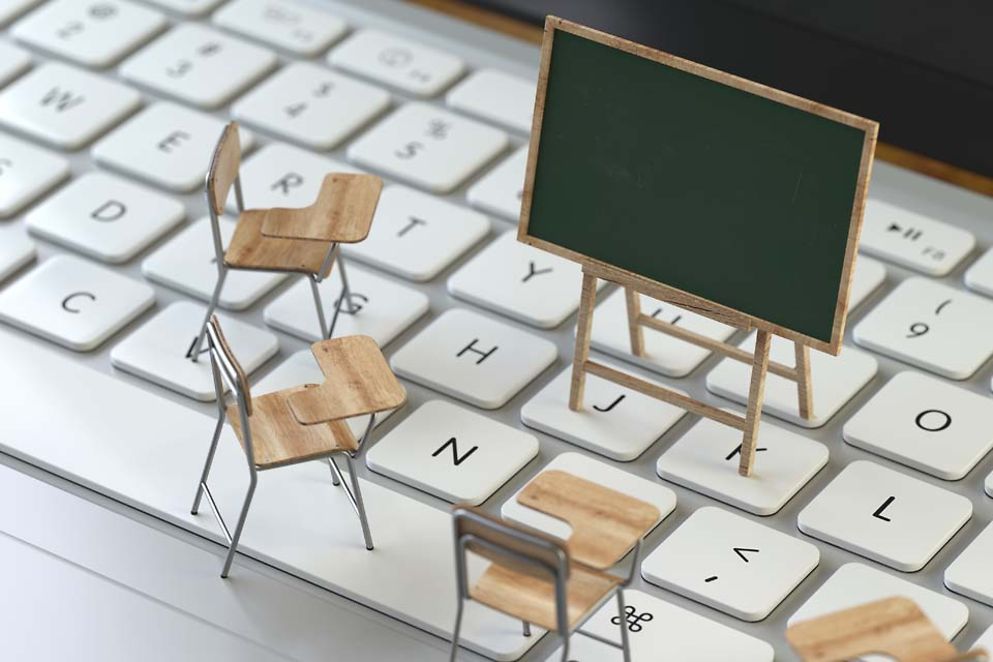 Kleine Miniatur-Stühle und eine Tafel stehen auf einer Tastatur.