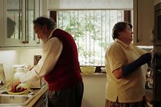 Ein älteres Paar steht rücken an Rücken in einer Küche.
