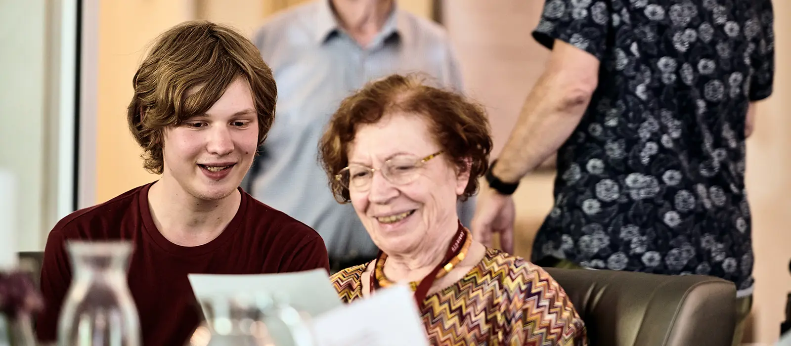 Eine Dame hält Papier in der Hand und schaut sich dieses mit einem Jungen an.