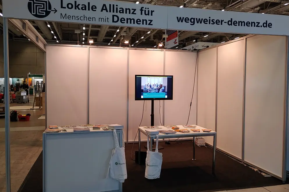 Auf den Tischen des Ausstellerstandes liegen viele Broschüren aus.