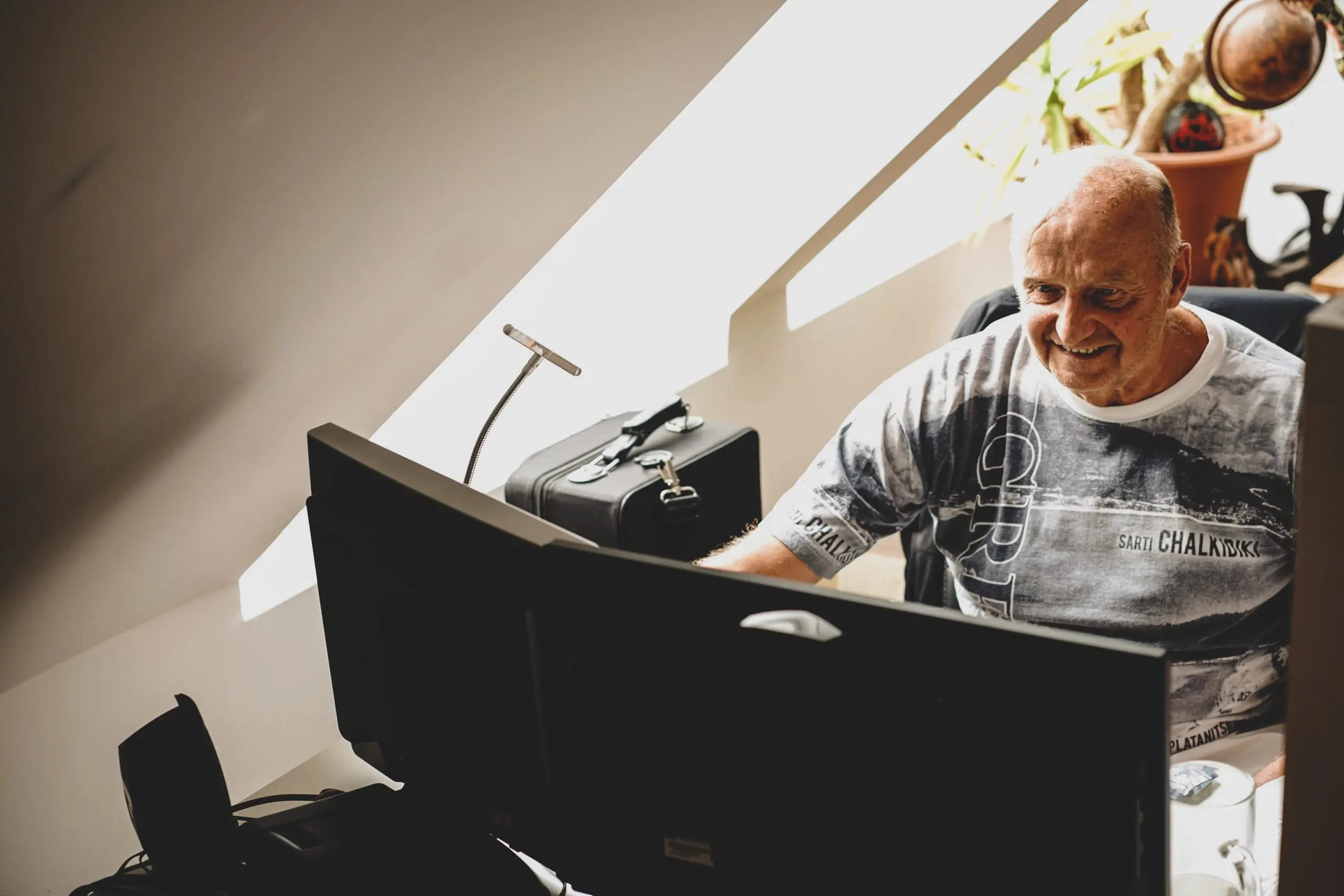 Ein Mann sitzt lächelnd vor einem Computer.